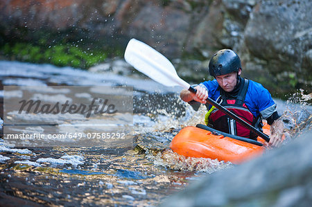Mid adult man kayaking on river rapids