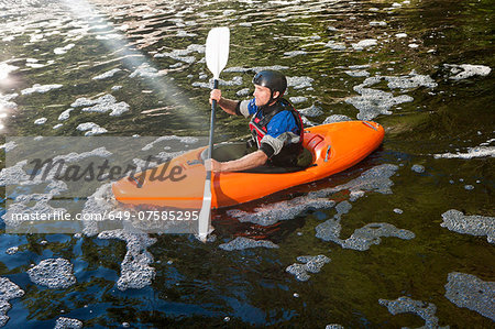 Mid adult man kayaking on peaceful river Mid adult man kayaking on peaceful river