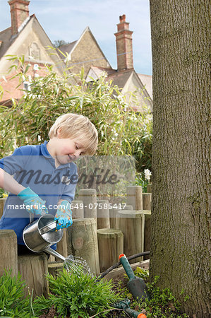School boy watering plants in garden