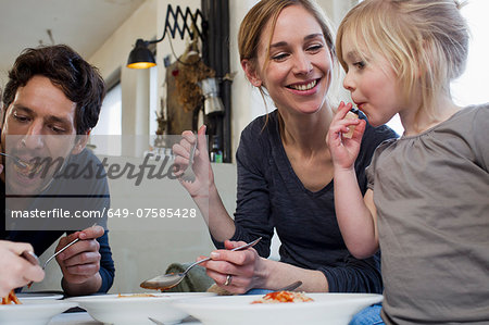 Mid adult parents and two daughters eating a spaghetti meal