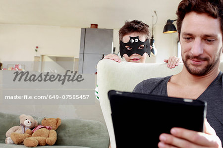 Masked son distracting father from digital tablet