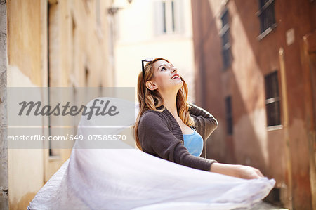 Young woman swirling her scarf on street, Rome, Italy