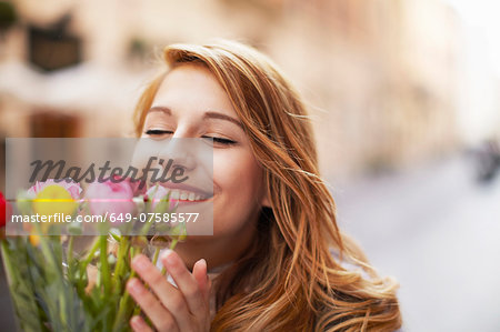 Smiling young woman smelling a bunch of flowers