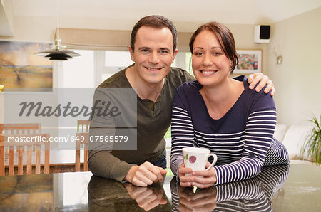 Portrait of mid adult couple leaning on kitchen counter