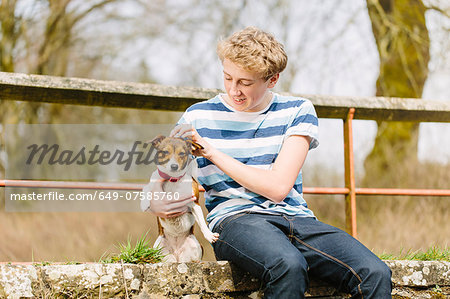 Teenage boy sitting on footbridge with his jack russell dog