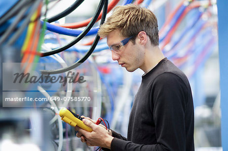 Mid adult male technician testing cables in engineering plant