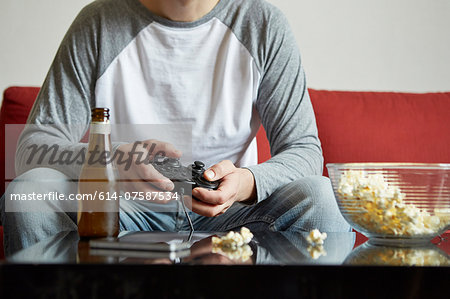 Mid adult man sitting on sofa using computer game control