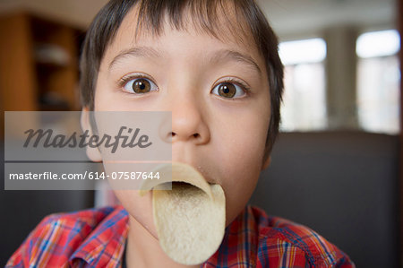 Boy imitating bird beak with crisps