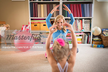 Mother and young daughter practicing ballet in sitting room