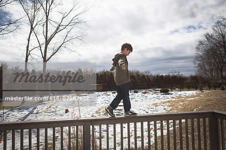 Boy walking along top of fence in park