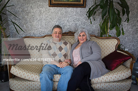 Portrait of mature couple sitting on ornate sofa