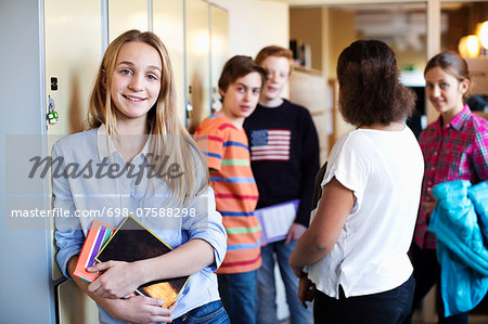 Portrait Of School Girl Standing At Locker Room With Friends