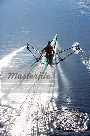 Man rowing scull on lake