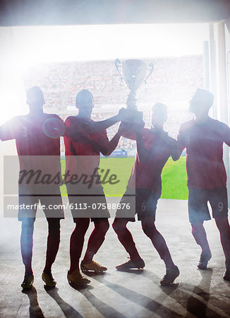 Silhouette of soccer players holding trophy