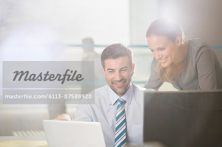 Businessman and businesswoman using laptop in office