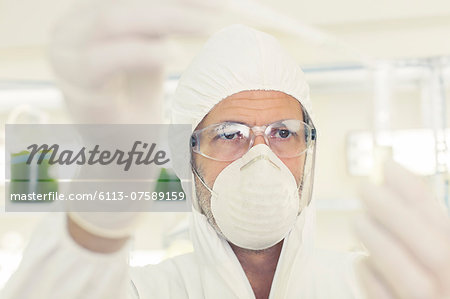 Scientist in clean suit with pipette and test tube