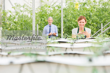 Portrait of botanists examining plants in greenhouse