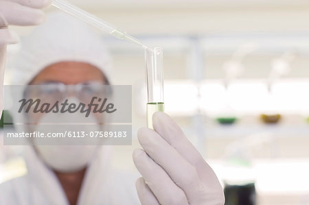 Scientist in clean suit using pipette and test tube in laboratory