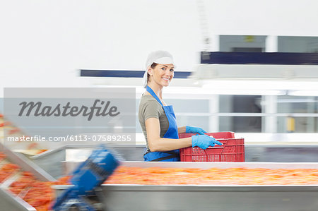 Portrait of confident worker carrying crate in food processing plant