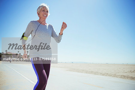 Senior woman jogging on beach boardwalk