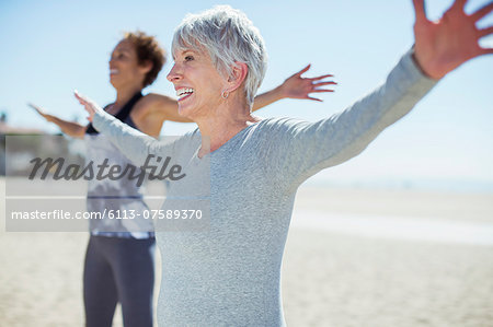 Senior women stretching arms on beach