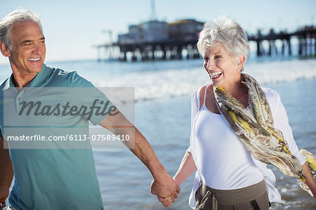 Enthusiastic senior couple running on beach