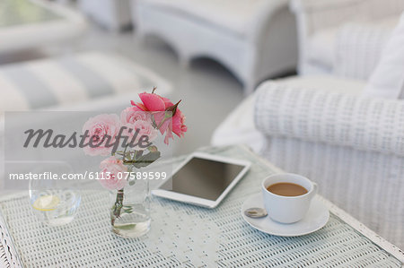 Pink roses on patio table with coffee cup and digital tablet Pink roses on patio table with coffee cup and digital tablet