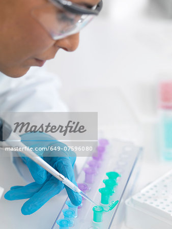 Female scientist pipetting DNA samples for analysis Female scientist pipetting DNA samples for analysis