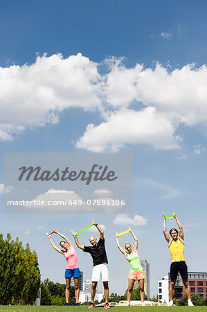 Four people training with rubber exercise bands in park