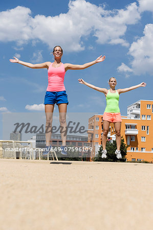 Two young women doing jump exercises in park