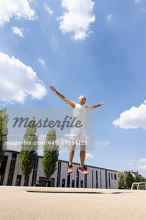 Mature man doing jump exercise in park