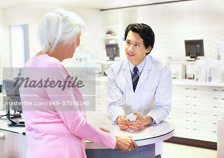 Male pharmacist advising customer on medication