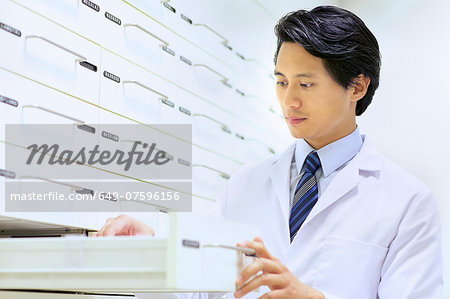 Male pharmacist searching for medications in pharmacy