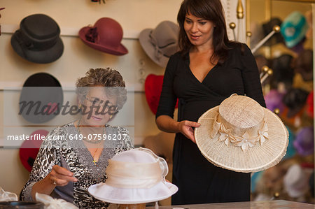 Milliner adjusting hat for customer in shop