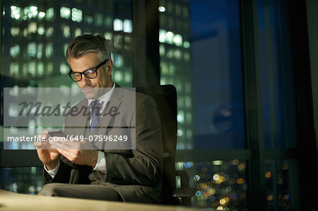 Businessman working late texting on smartphone Businessman working late texting on smartphone