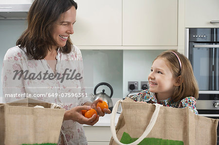 Mother and young daughter unpacking shopping bags