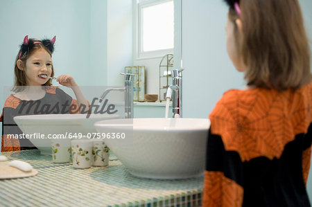 Girl in fancy dress costume brushing her teeth
