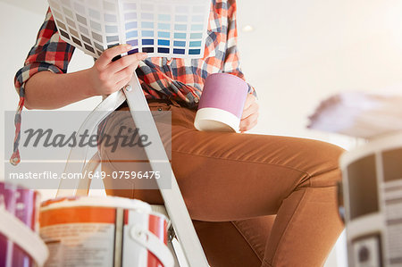 Teenage girl sitting on stepladders with coffee and swatch