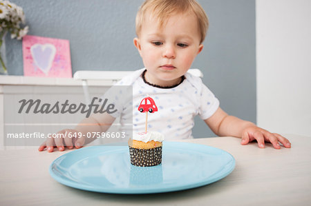 Baby boy looking at cupcake