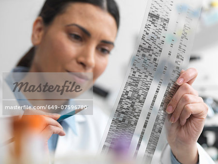 Female scientist examining DNA gel in laboratory for genetic research