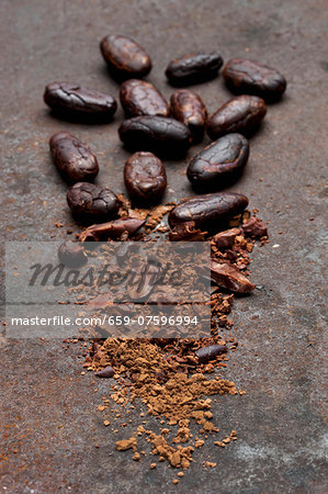 Peeled whole cocoa beans, broken pieces and cocoa on a rusty surface