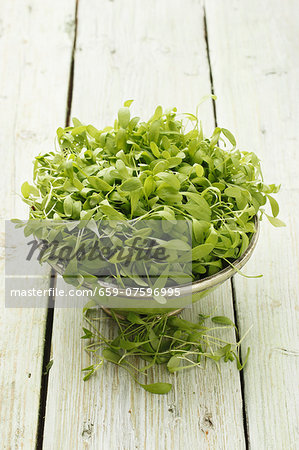 Fresh watercress in a bowl on a wooden surface