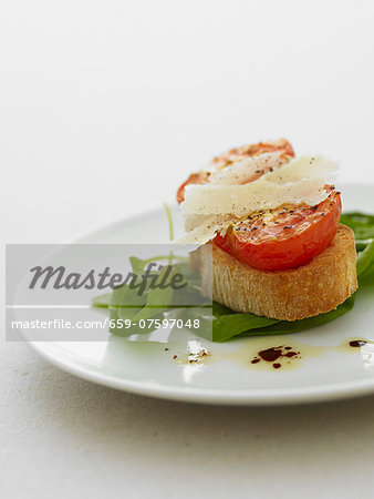 Grilled tomato on bruschetta with parmesan on a bed of spinach Grilled tomato on bruschetta with parmesan on a bed of spinach