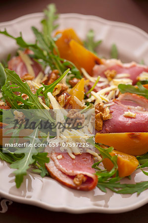 A salad of boiled ham, rocket, walnuts, yellow plums and cheese