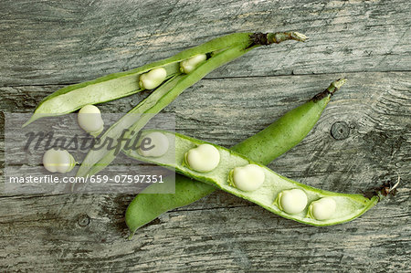 Broad beans in the pod on a wooden surface