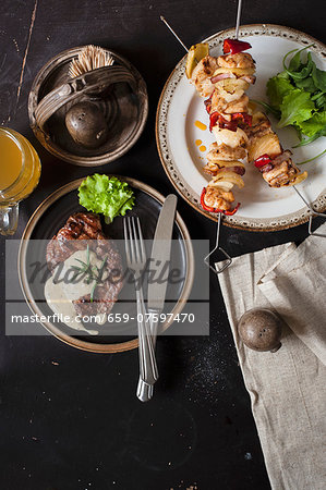 Grilled steak and chicken skewers on a plate (view from above)