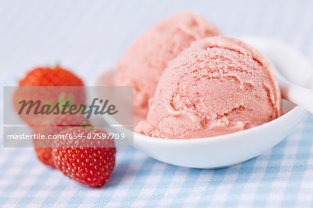 A few fresh strawberries alongside two scoops of home-made strawberry ice cream