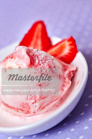 A scoop of frozen yoghurt with strawberries in a shallow dish