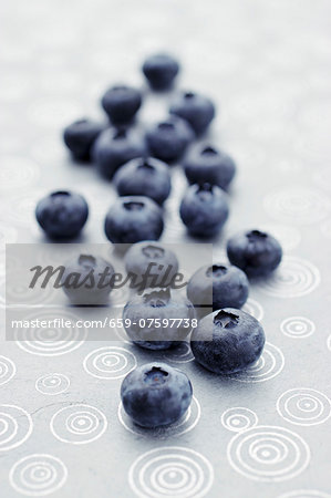 Fresh blueberries lying on a patterned tablecloth (close-up) Fresh blueberries lying on a patterned tablecloth (close-up)