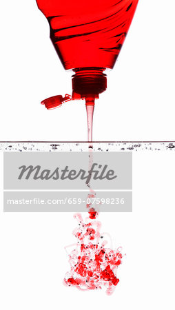 Red washing-up liquid running into water Red washing-up liquid running into water